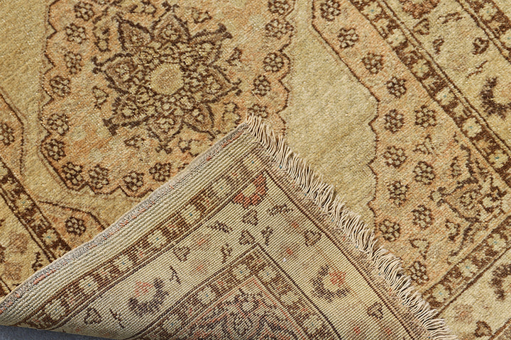 Small antique Haji Jalili design Persian rug featuring tan and gold medallion open field with intricate spandrels and border