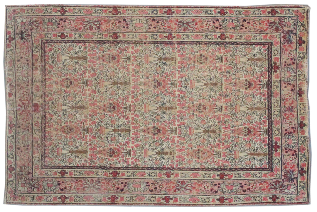 Antique Persian Kerman wool rug featuring an allover floral design with intricate palmettes and vine scrolls in soft pink, ivory, and deep navy blue