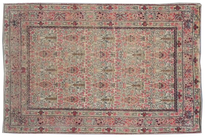 Antique Persian Kerman wool rug featuring an allover floral design with intricate palmettes and vine scrolls in soft pink, ivory, and deep navy blue