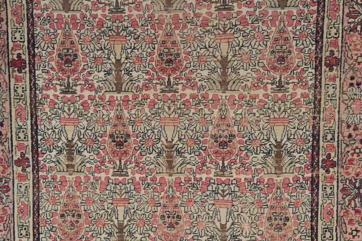 Antique Persian Kerman wool rug featuring an allover floral design with intricate palmettes and vine scrolls in soft pink, ivory, and deep navy blue