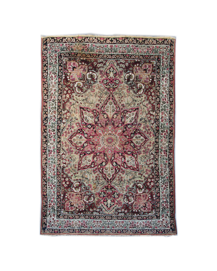 Antique Persian Kermanshah wool rug featuring a dark navy central medallion surrounded by floral motifs in ivory, pink, red, and tan
