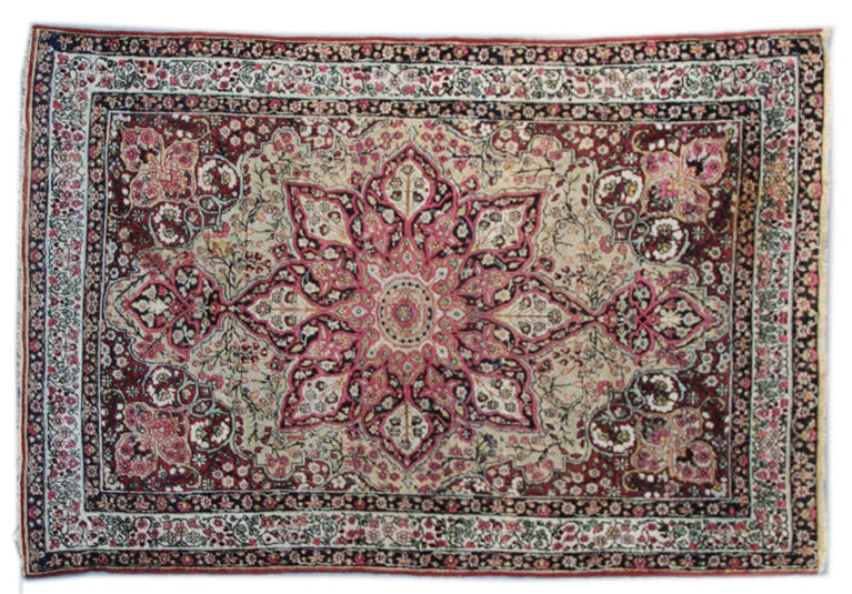 A floral patterned rug with a central medallion design, predominantly in pink and green colors, with a Persian style border.
