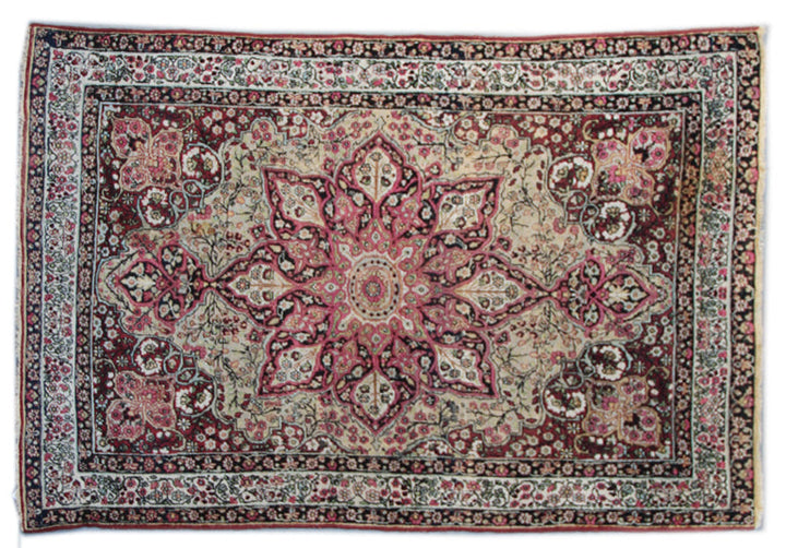 A floral patterned rug with a central medallion design, predominantly in pink and green colors, with a Persian style border.