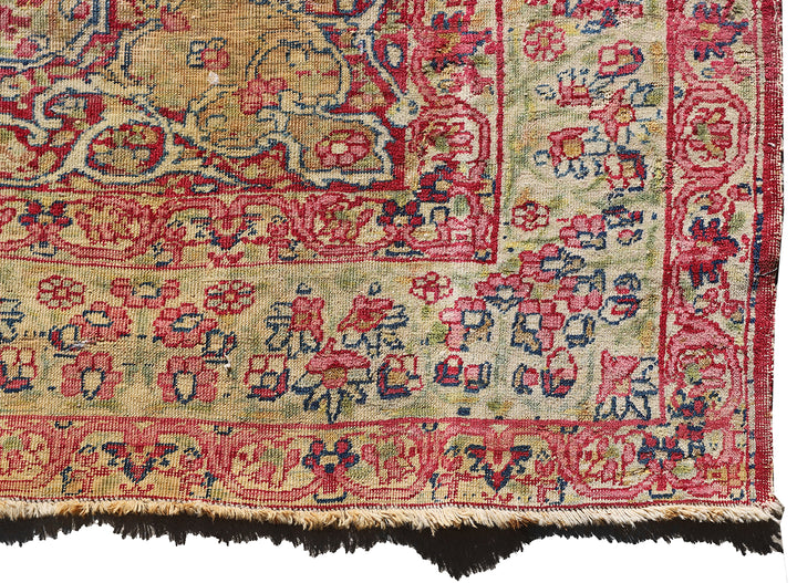 Late 19th-century antique Persian Kermanshah rug featuring a dark navy center medallion on an ivory floral field with pink, red, and blue botanical details