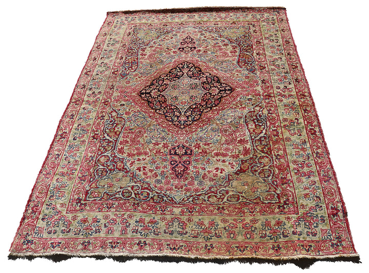 Late 19th-century antique Persian Kermanshah rug featuring a dark navy center medallion on an ivory floral field with pink, red, and blue botanical details