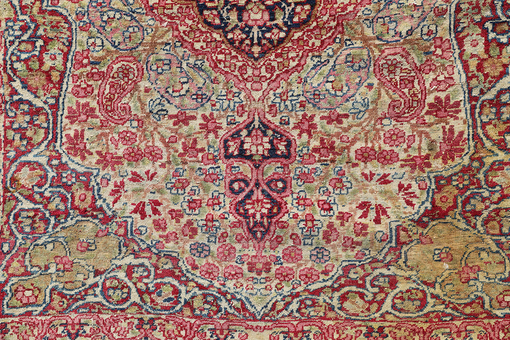 Late 19th-century antique Persian Kermanshah rug featuring a dark navy center medallion on an ivory floral field with pink, red, and blue botanical details
