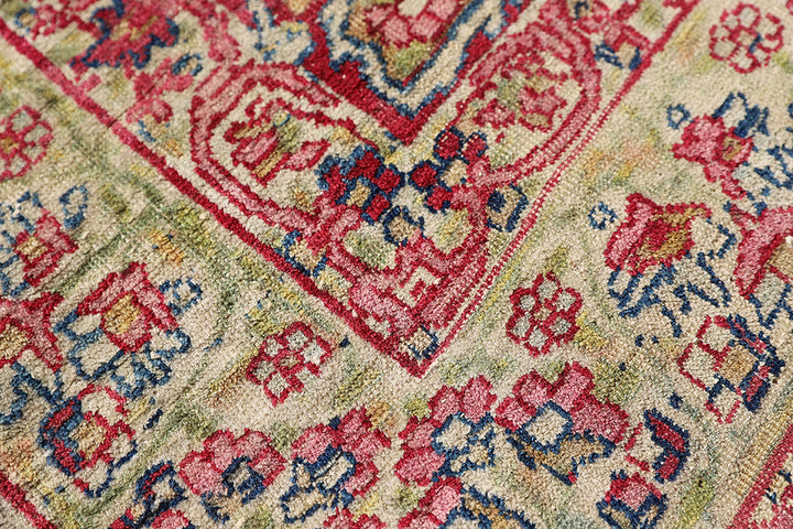 Late 19th-century antique Persian Kermanshah rug featuring a dark navy center medallion on an ivory floral field with pink, red, and blue botanical details