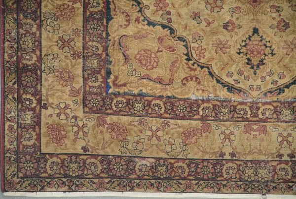 Antique Persian Kermanshah wool area rug with a central floral medallion in warm tan and deep navy blue with low pile