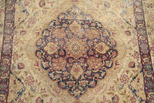 Antique Persian Kermanshah wool area rug with a central floral medallion in warm tan and deep navy blue with low pile