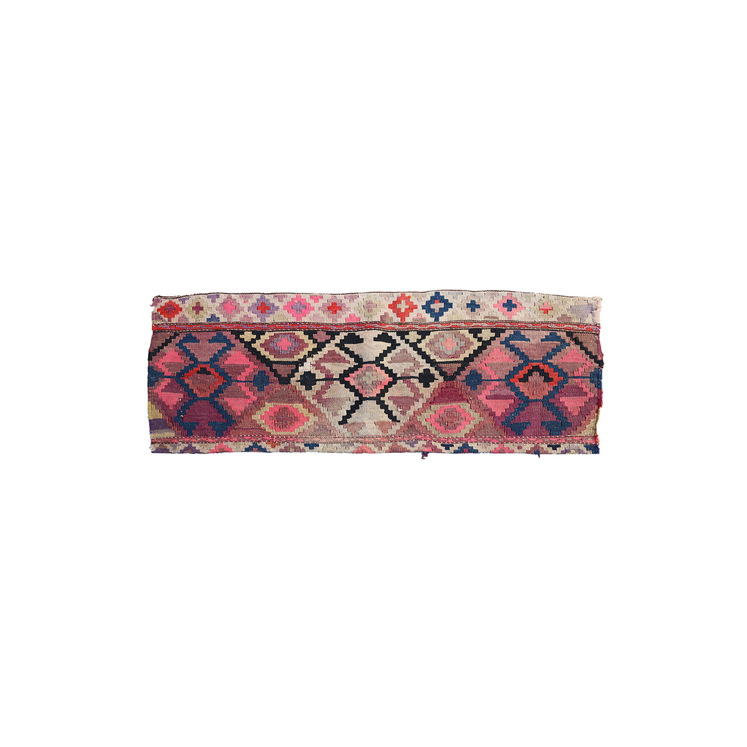 A rectangular vintage kilim rug band with geometric patterns in pink, red, blue, and beige on a white background.