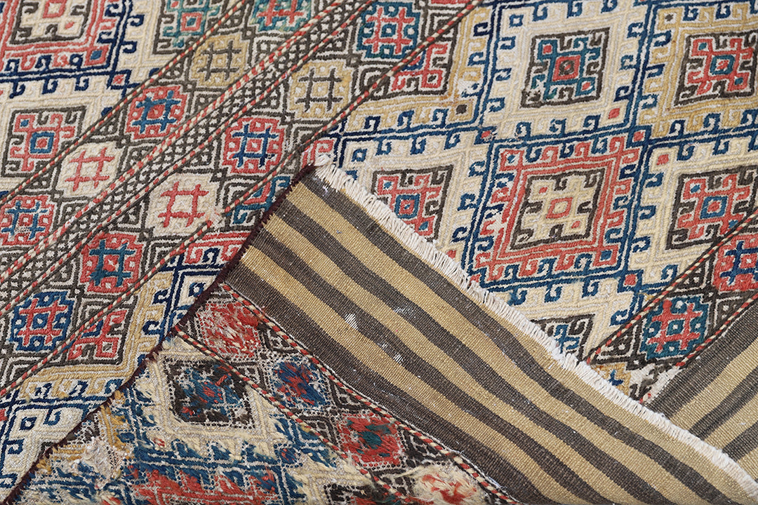 Close-up of a patterned rug with geometric designs in red, blue, and beige.