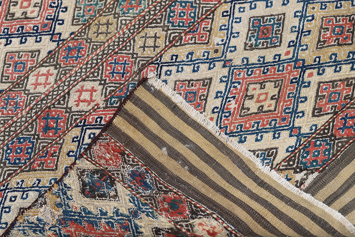 Close-up of a patterned rug with geometric designs in red, blue, and beige.