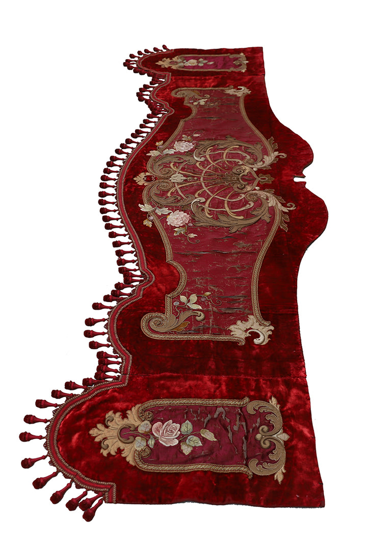 Decorative red fabric with intricate gold embroidery on a white background