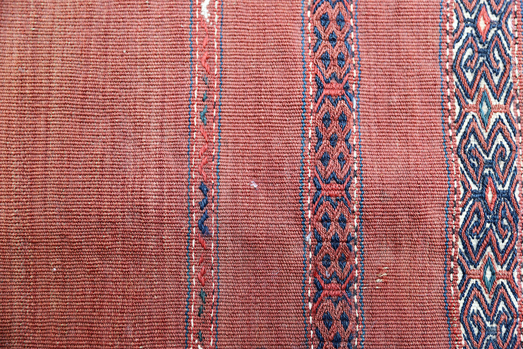 Close-up of a textured fabric with intricate patterns on a red-brown background