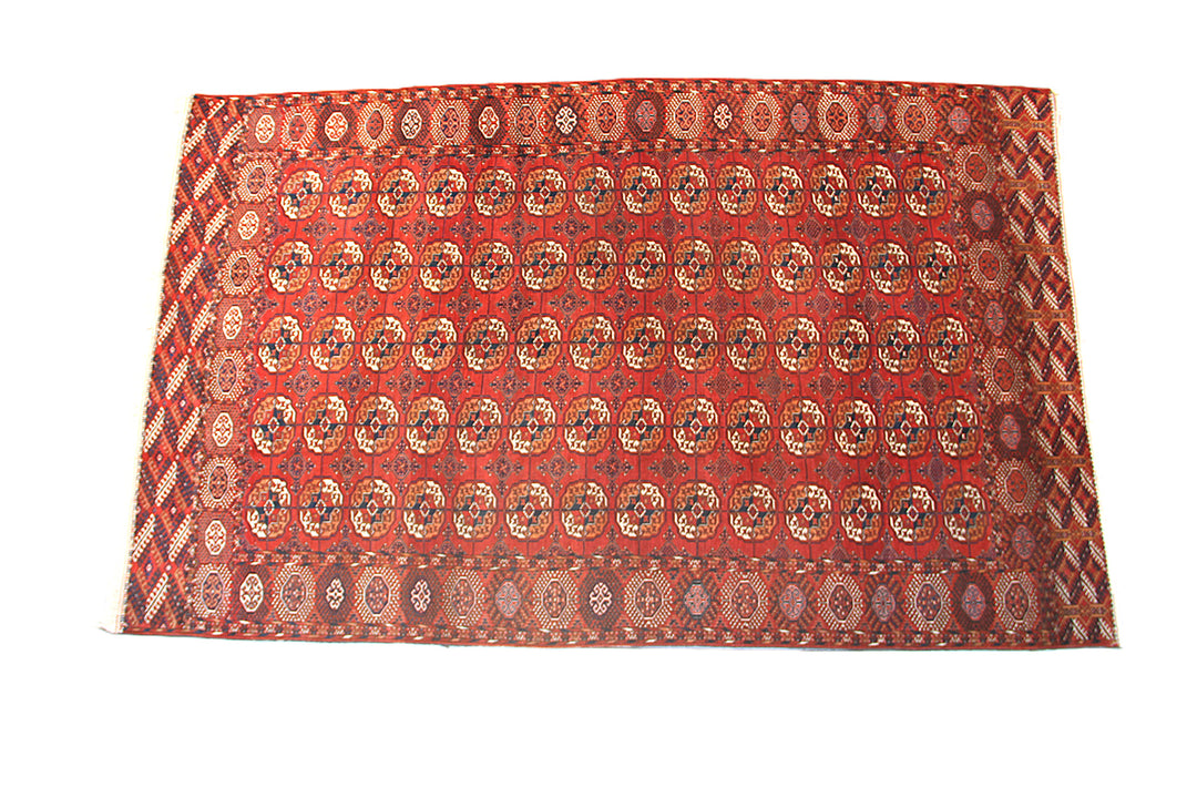 12'2" x 7'6" semi-antique Turkmen main carpet featuring a deep red field with hand-knotted geometric octagonal gul motifs and tribal borders.