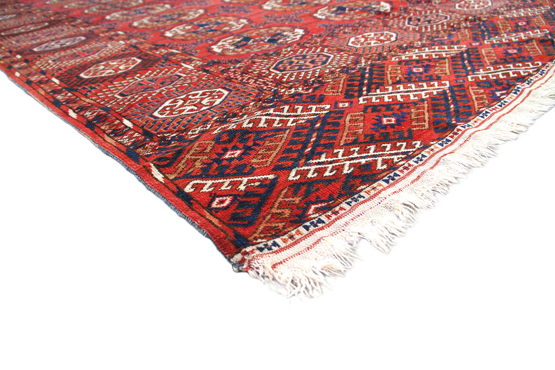 12'2" x 7'6" semi-antique Turkmen main carpet featuring a deep red field with hand-knotted geometric octagonal gul motifs and tribal borders.