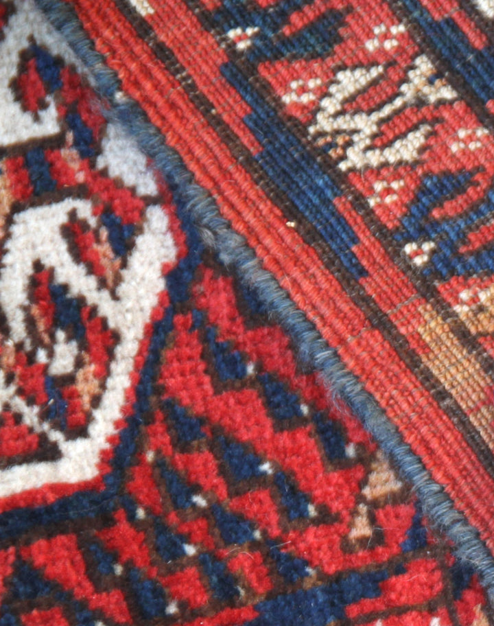 12'2" x 7'6" semi-antique Turkmen main carpet featuring a deep red field with hand-knotted geometric octagonal gul motifs and tribal borders.