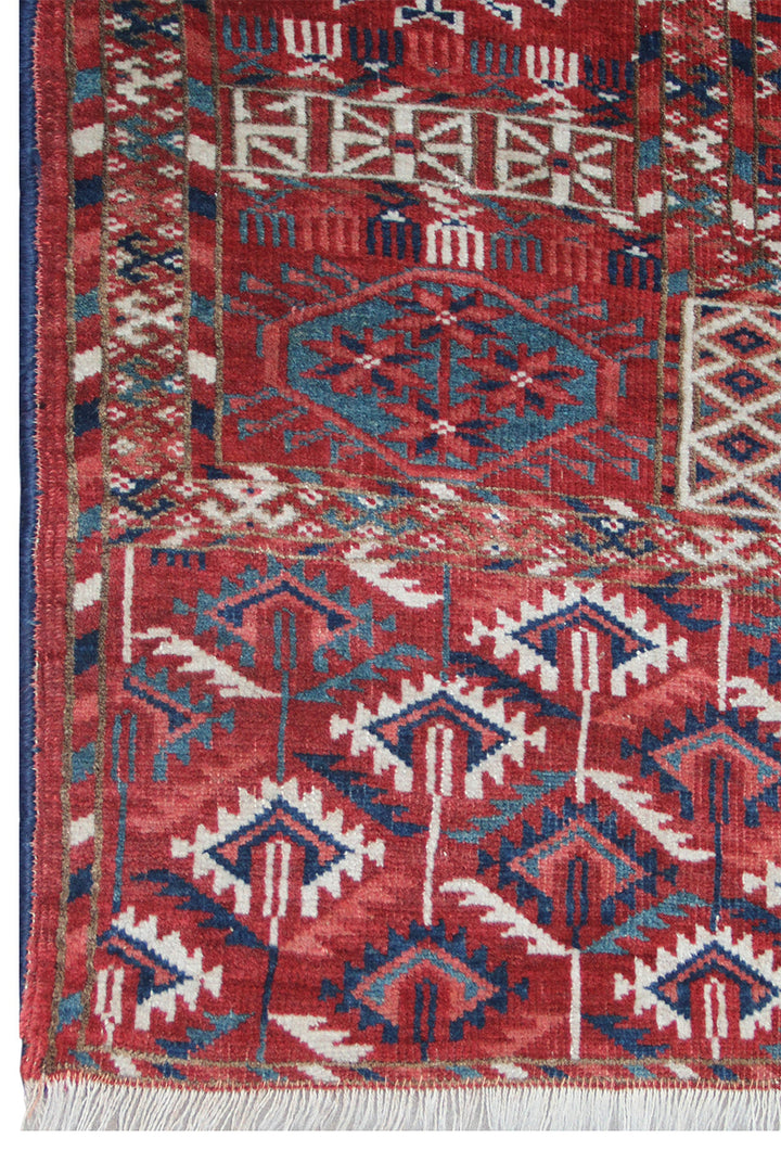 11'1" x 7'1" Antique Turkmen main rug featuring a deep red background with hand-knotted geometric motifs in navy, green, white, and brown.