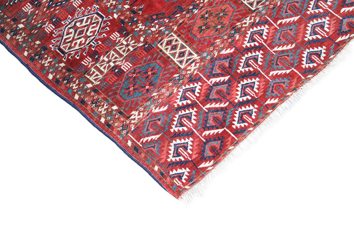 11'1" x 7'1" Antique Turkmen main rug featuring a deep red background with hand-knotted geometric motifs in navy, green, white, and brown.