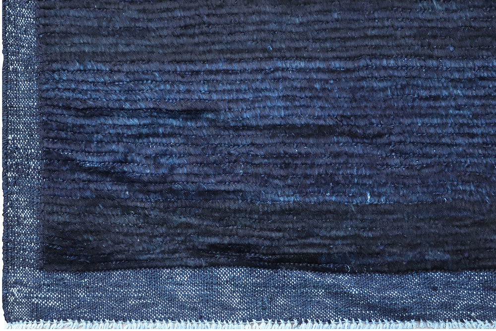 Hand-knotted 6'3" x 9'2" Moroccan-style solid deep blue wool area rug with a rich, soft pile from the Ariana Barchi Collection.
