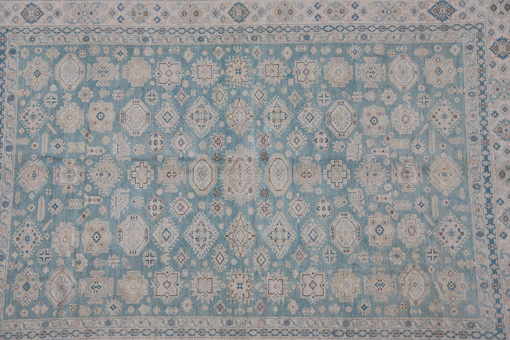 Authentic Ariana Hazara Collection 10x14 wool area rug. Features a geometric Caucasian design with a blue field, black, white, and pink accents, hand-knotted by Hazara women in Afghanistan.