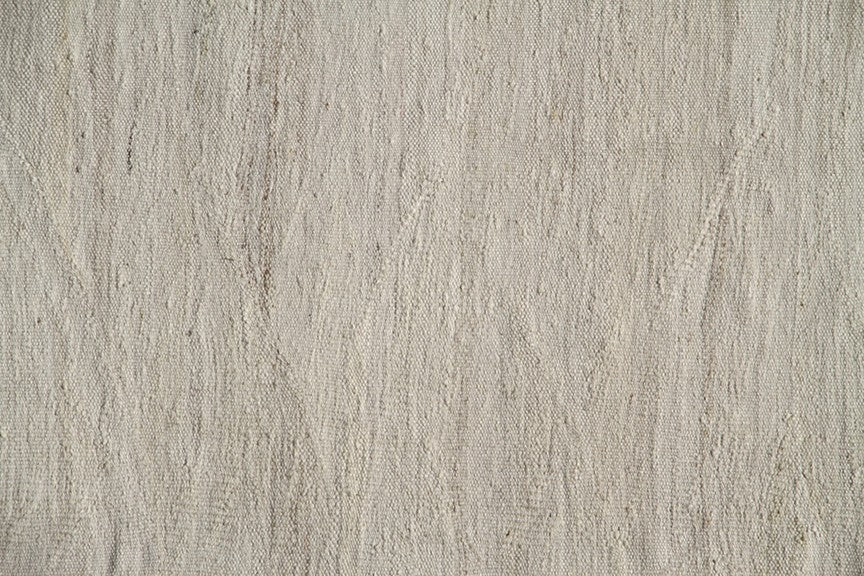 Large earth-tone flatweave Ariana kilim rug in natural undyed organic wool with subtle woven texture.