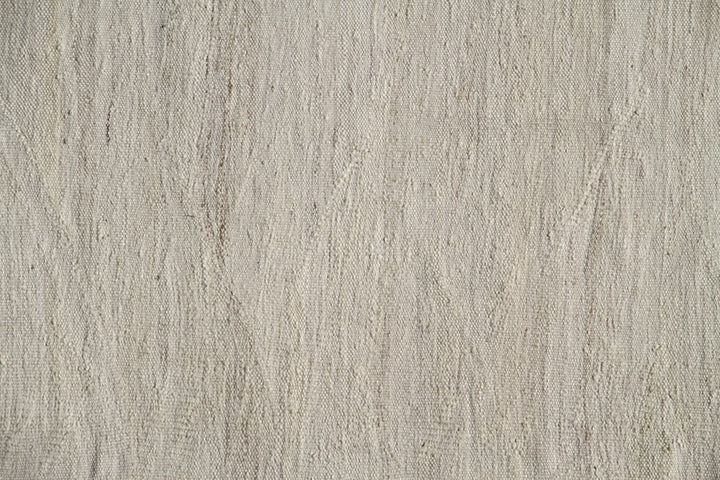 Large earth-tone flatweave Ariana kilim rug in natural undyed organic wool with subtle woven texture.