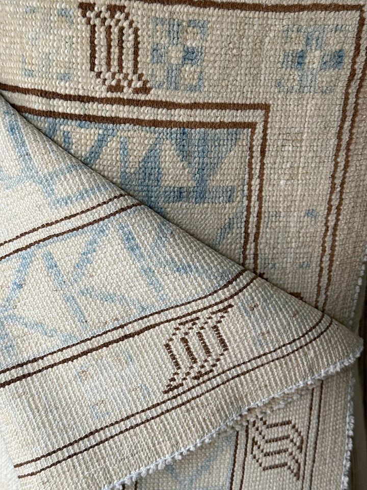Ariana large Caucasian design wool rug in ivory and pale blue, hand-knotted in Afghanistan by Hazara artisans. Luxury oversized geometric area rug for elegant interiors.
