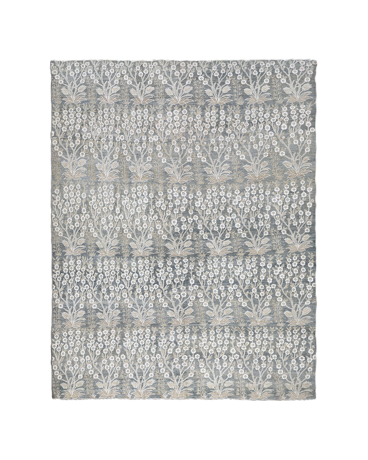 Ariana Transitional 8x11 hand-knotted Afghan wool rug featuring a directional blue millfleur tree design with stark white cotton floral accents.