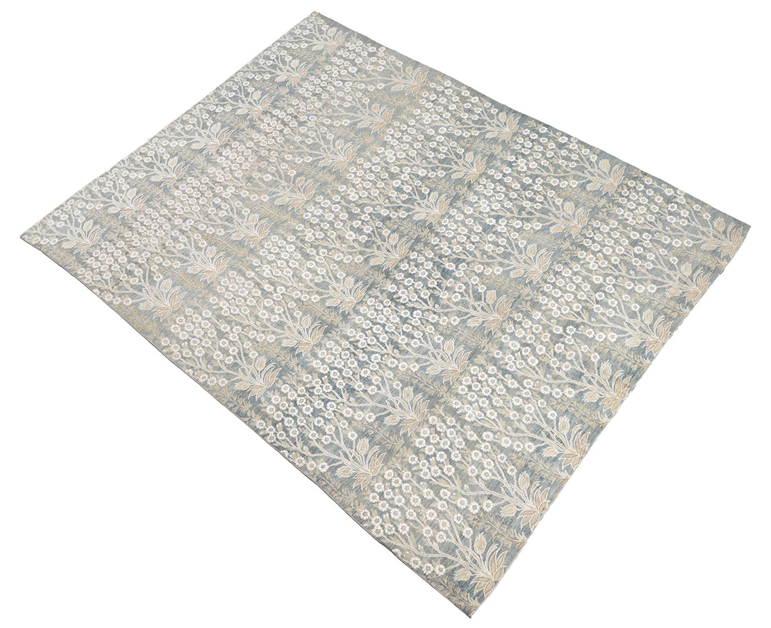 Ariana Transitional 8x11 hand-knotted Afghan wool rug featuring a directional blue millfleur tree design with stark white cotton floral accents.
