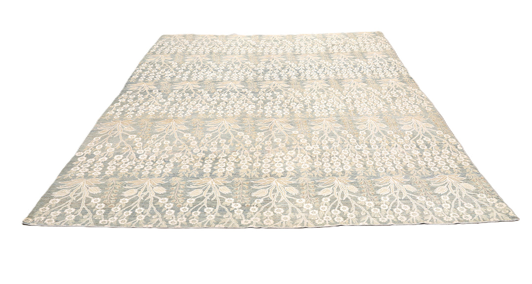 Ariana Transitional 8x11 hand-knotted Afghan wool rug featuring a directional blue millfleur tree design with stark white cotton floral accents.