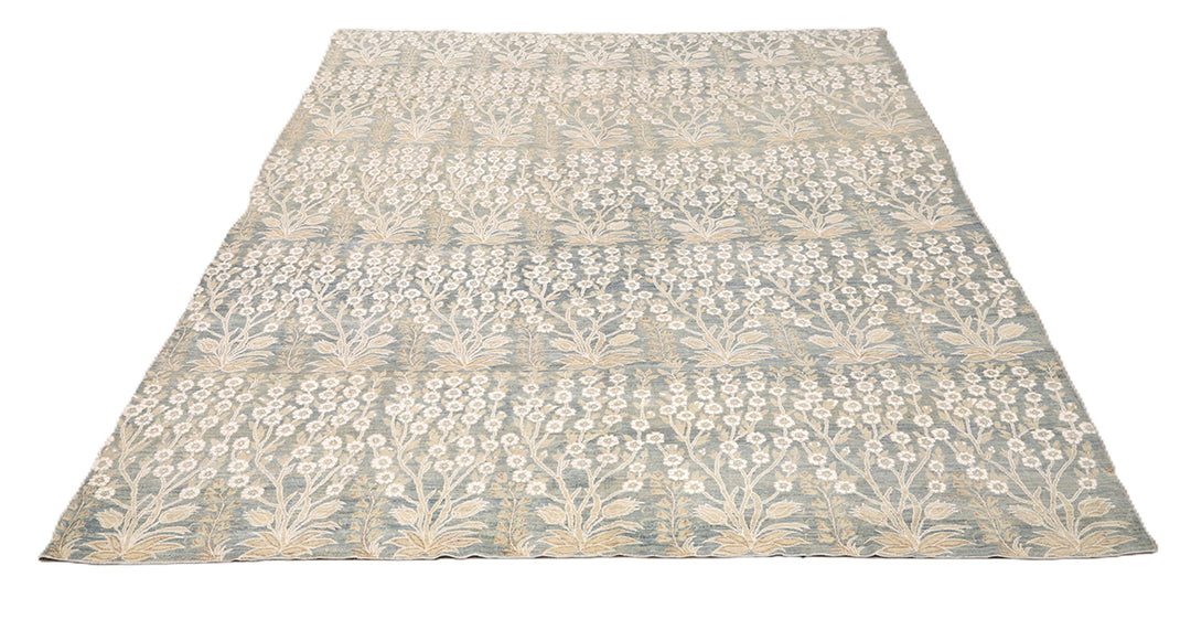 Ariana Transitional 8x11 hand-knotted Afghan wool rug featuring a directional blue millfleur tree design with stark white cotton floral accents.