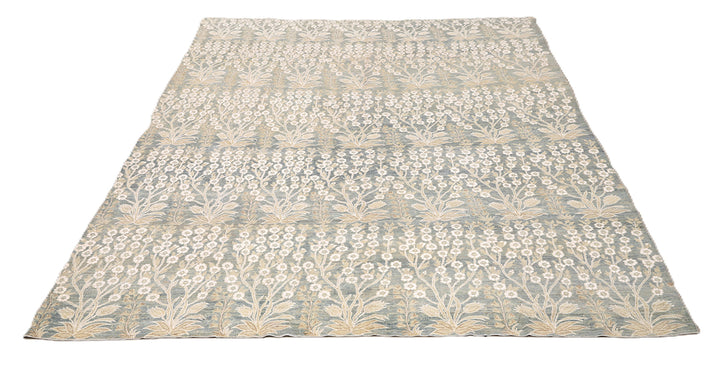 Ariana Transitional 8x11 hand-knotted Afghan wool rug featuring a directional blue millfleur tree design with stark white cotton floral accents.