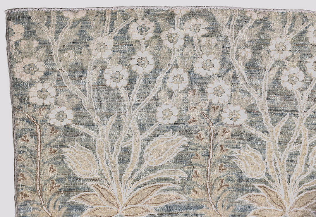Ariana Transitional 8x11 hand-knotted Afghan wool rug featuring a directional blue millfleur tree design with stark white cotton floral accents.