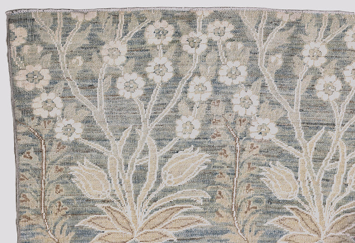 Ariana Transitional 8x11 hand-knotted Afghan wool rug featuring a directional blue millfleur tree design with stark white cotton floral accents.