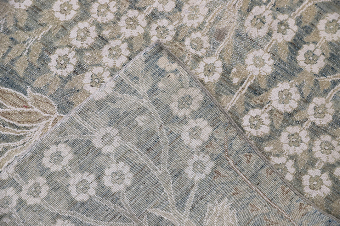 Ariana Transitional 8x11 hand-knotted Afghan wool rug featuring a directional blue millfleur tree design with stark white cotton floral accents.