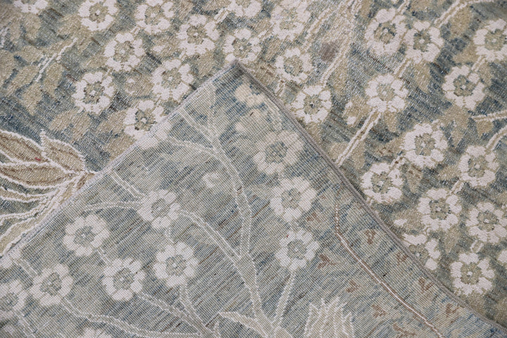Ariana Transitional 8x11 hand-knotted Afghan wool rug featuring a directional blue millfleur tree design with stark white cotton floral accents.