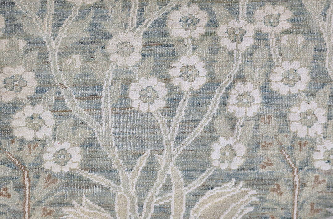 Ariana Transitional 8x11 hand-knotted Afghan wool rug featuring a directional blue millfleur tree design with stark white cotton floral accents.