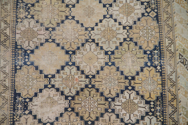 Distressed antique Caucasian Shirvan wool rug featuring geometric motifs in navy blue and tan with heavy distress and authentic age patina