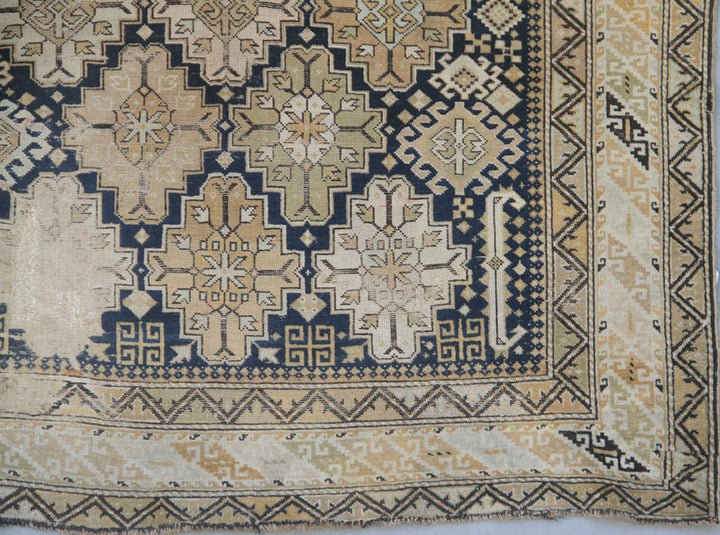 Distressed antique Caucasian Shirvan wool rug featuring geometric motifs in navy blue and tan with heavy distress and authentic age patina
