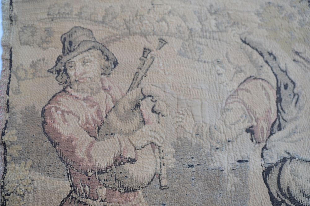 Early 20th-century French power-loomed tapestry depicting a man playing a pipe instrument and a man dancing in a pastoral setting, measuring 3 feet by 4 feet