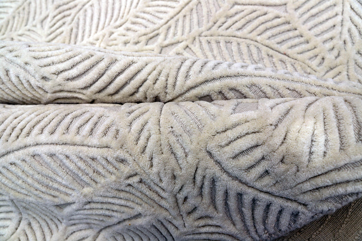 White hand-loomed New Zealand wool area rug with over-tufted floral textured design.