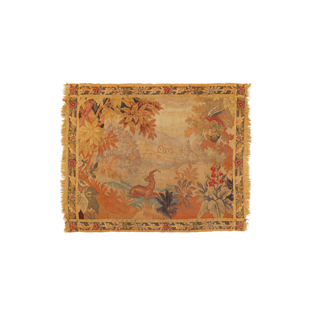 A square woven tapestry with fringed edges, featuring a vintage-style landscape scene in warm autumnal tones of orange, beige, brown, and muted green, isolated on a white background.