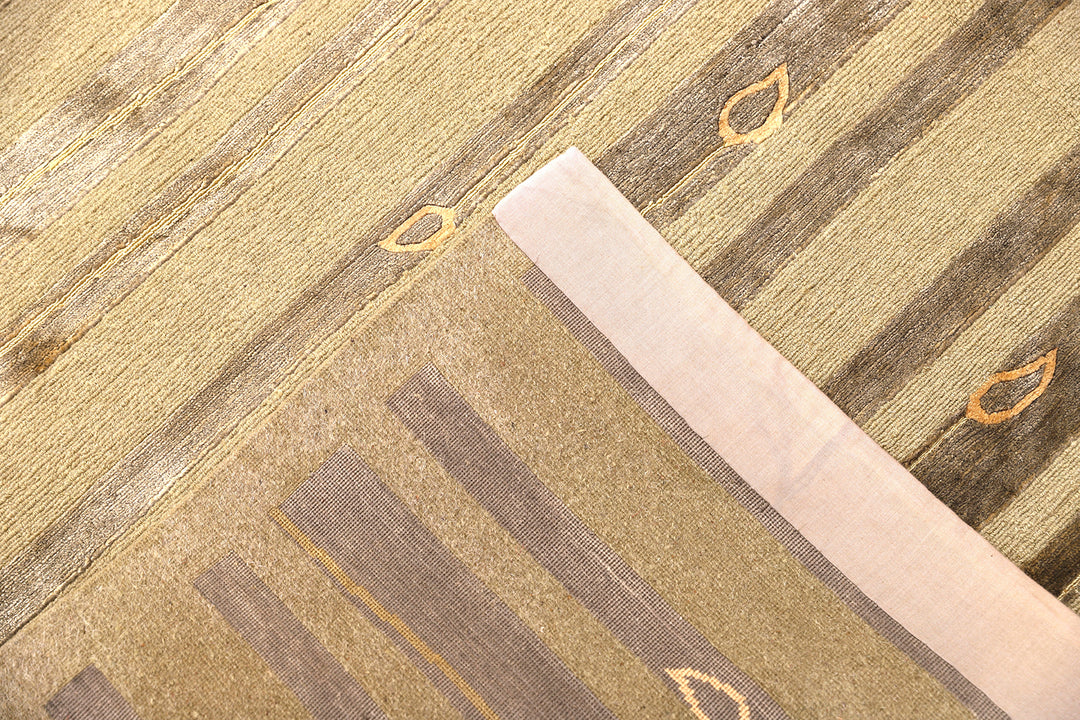 Hand-knotted Modern Tibetan Ariana rug in wool and silk featuring a geometric pattern in gold and greenish hues