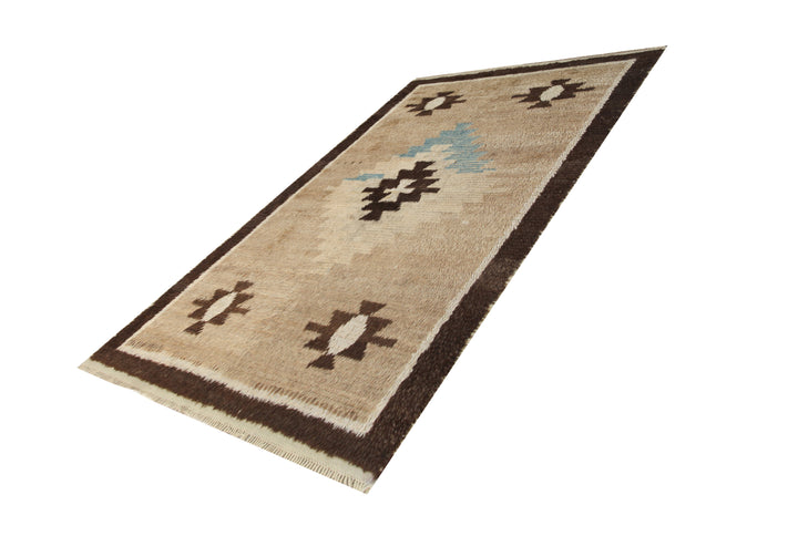 A 4x7 vintage Turkish Tulu rug featuring a shaggy brown wool pile with a central blue/brown medallion and four corner motifs.