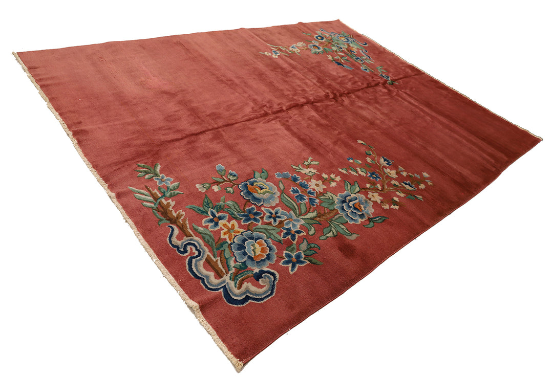 A 9x11 vintage Chinese Art Deco wool rug with a soft salmon pink background and sage green floral accents in the corners.