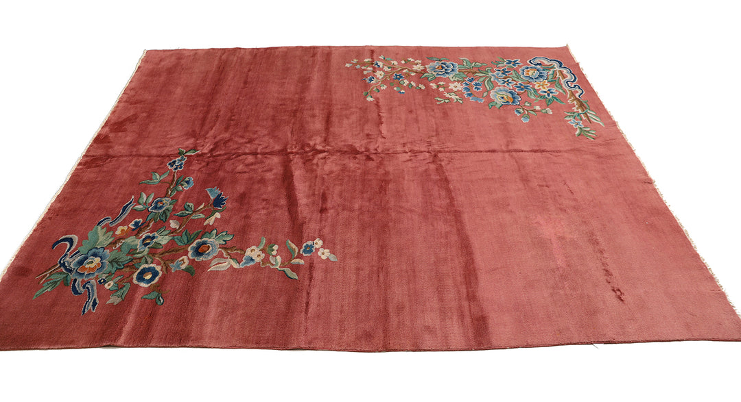 A 9x11 vintage Chinese Art Deco wool rug with a soft salmon pink background and sage green floral accents in the corners.