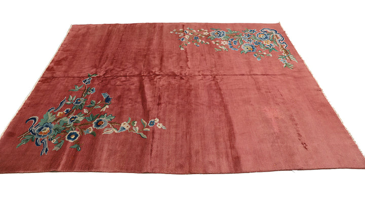 A 9x11 vintage Chinese Art Deco wool rug with a soft salmon pink background and sage green floral accents in the corners.