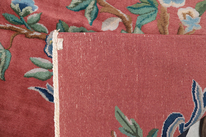 A 9x11 vintage Chinese Art Deco wool rug with a soft salmon pink background and sage green floral accents in the corners.