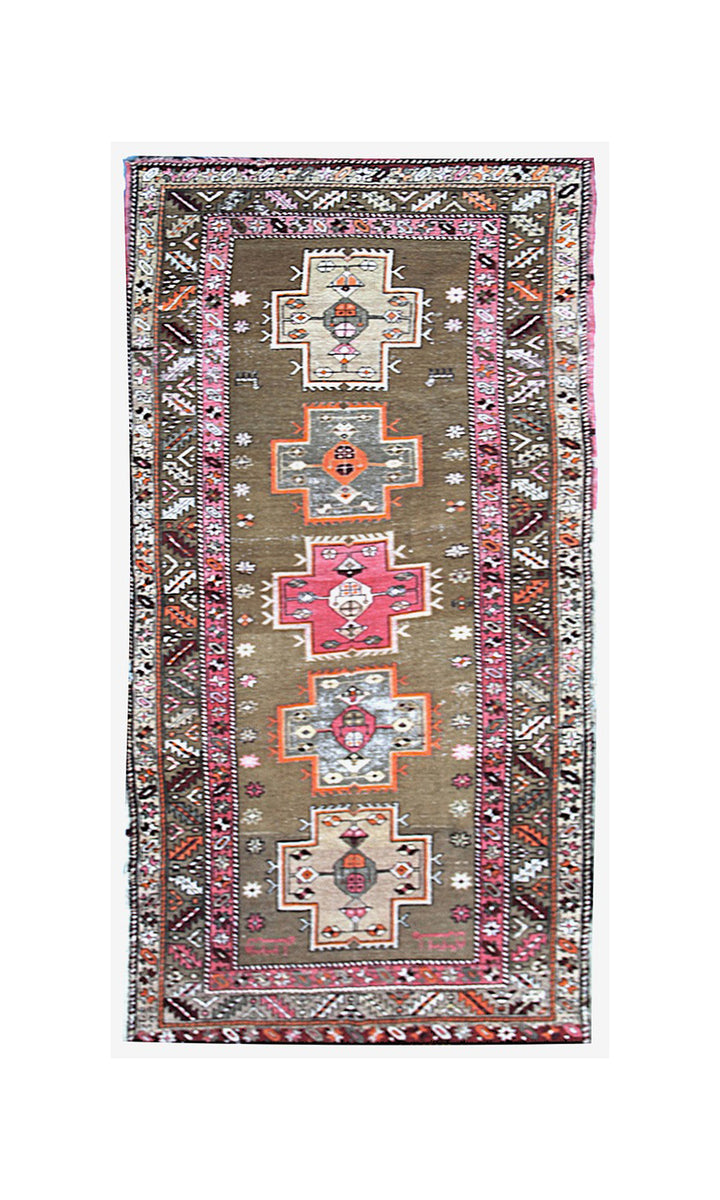 A rectangular vintage-style area rug with a brown field, four central medallions in pink, orange, and gray, and a detailed multicolor geometric border.